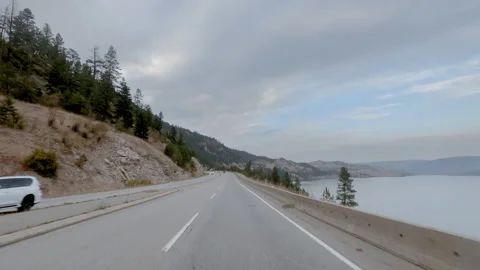 Driving along the road between hills with yellow grass, lake on the right Stock Footage 140952841