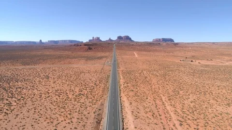 Driving along a straight empty road towards iconic Monument Valley landmark. Video stock 113648617