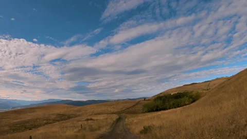 Driving along a winding path between hills covered with yellow grass Stock Footage 141532876