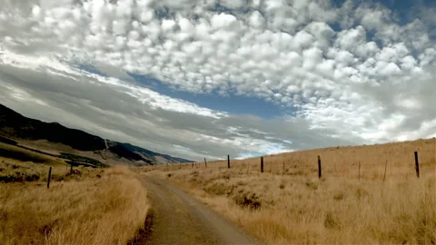 Driving along a winding path between hills covered with yellow grass Stock Footage 141559219