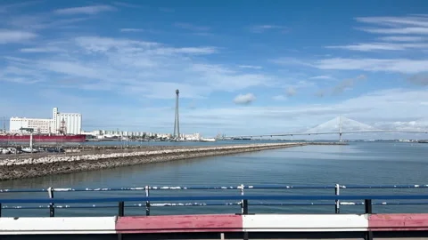 Driving alongside the sea with the constitution bridge on the horizon in Spain Stock Footage 337069733