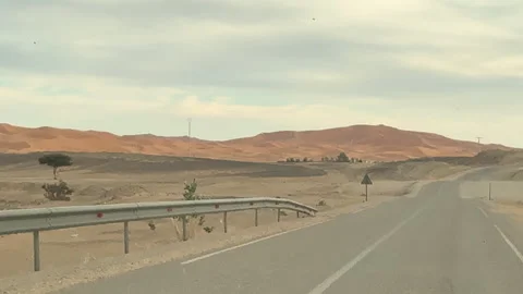 Driving on an asphalt road through a desert landscape with sand dunes Stock Footage 339557654