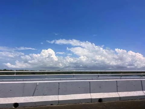 Driving on Bridge Clear Sky Dramatic Clouds Over Water Landscape Stock Photos