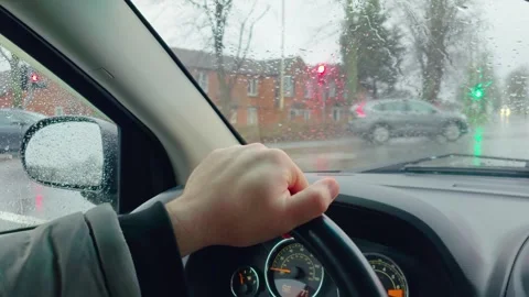 Driving car approaching roundabout during rainfall while yielding traffic Stock Footage 333246958