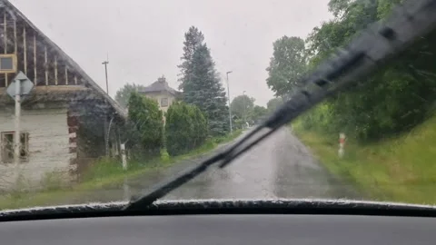Driving in a car on an asphalt road in a small village during heavy rain Stock Footage 310997861