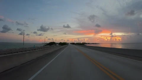Driving a car on empty Overseas Highway bridge at vibrant sunset Stock Footage 338314933