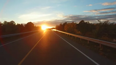 Driving a Car in Point of View Perspective on a Road into Sunset - Lens Flare Stock-Footage 84868716