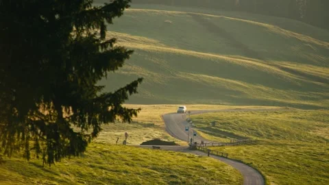 Driving a Car on a Winding Road Through Green Hills at Sunrise in the Dolomites Stock Footage 331163635