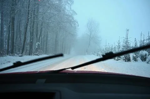 Driving the car in the winter. View from the interior of a car on a snowy roa Stock Photos