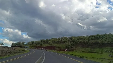 Driving on Curving Road Through Tree Covered Hills Under Cloudy Sky 動画素材 335489789