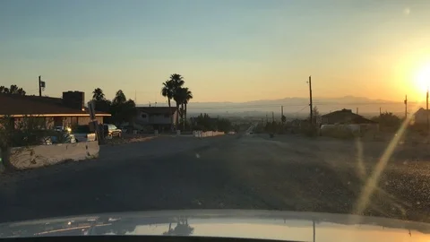 Driving down bumpy road at sunset in desert city Stock Footage 91266168