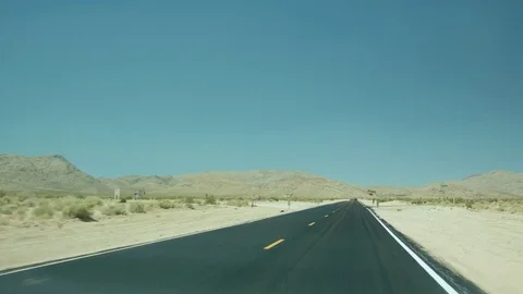 Driving down a clear motorway with mountainous peaks in the background 스톡 동영상 79851142