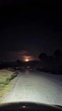 Driving down a deserted road under a bright moonlit night Stock Photos