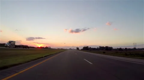 Driving down a highway at sunset among trees 库存影片 51738697