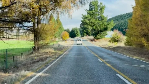 Driving down scenic road with trees in autumn colors and a van ahead. 스톡 동영상 332597788