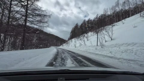 Driving Downhill Snowy Open Mountain Road Light Snowfall POV Stock Footage 333370635