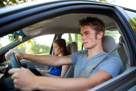 Driving: driver paying attention while passenger texts Stock Photos