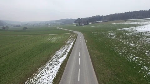 Driving on an empty asphalt road through the wheat fields with snow and fog. Stock Footage 120959650