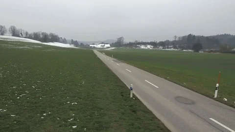 Driving on an empty asphalt road through the wheat fields with snow and fog. Stock Footage 120959838