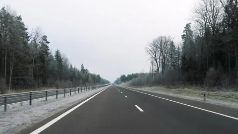 Driving on an empty highway through frosty winter forest Stock Footage 323360985