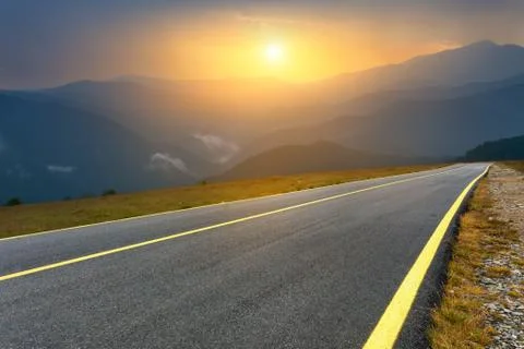 Driving on empty mountain road at sunset 写真素材