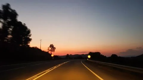 Driving on empty road at sunset Stock Photos