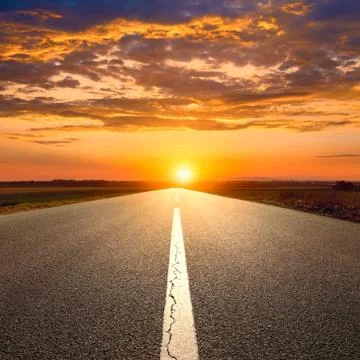 Driving on an empty road towards the sunset 写真素材