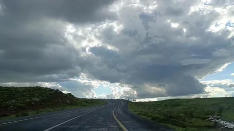 Driving on Empty Road Under Dark Storm Clouds and Blue Sky 動画素材 335489046
