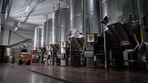 Driving a forklift with a driver through the territory of a winery with tanks Stock Footage 268750396