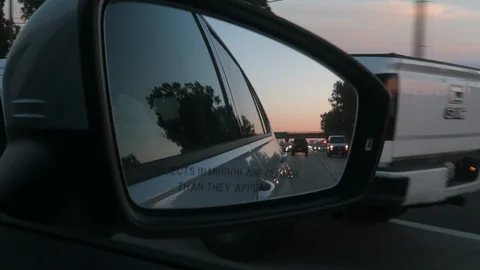 Driving on the freeway at sunset looking in the rearview mirror￼ Stockbeeldmateriaal 119184046