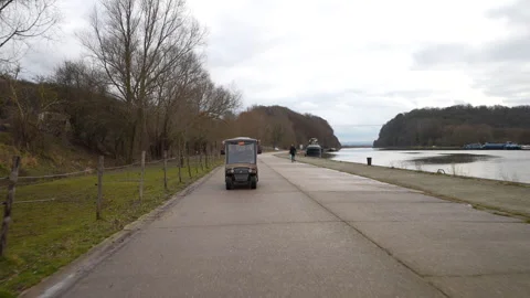 Driving golf cart on river side in Belgium, front view Stockbeeldmateriaal 331224841