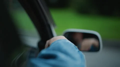 Driving hand on rolled window evening, denim jacket sleeve rests on door, soft Video stock 331072727