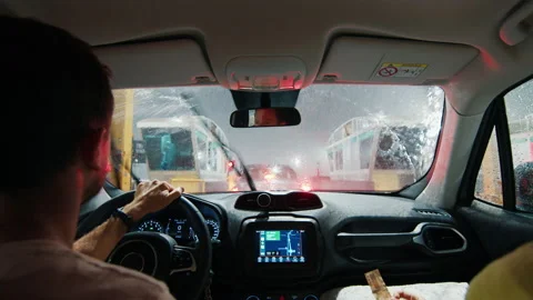 Driving at heavy rain. Man driver sits in the car and waits in a queue to pay Stock Footage 237016348