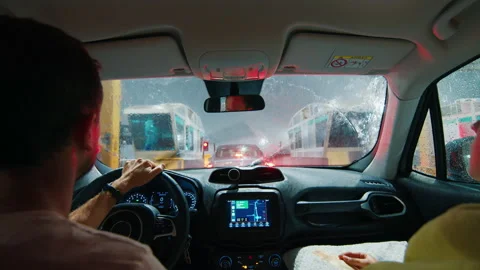 Driving at heavy rain. Man driver sits in the car and waits in a queue to pay Stock Footage 237399767