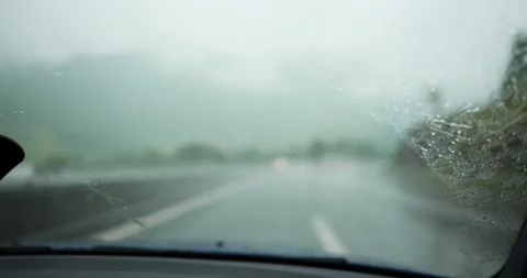 Driving in heavy rain with windshield wipers clearing water from the glass Stock Footage 336048675