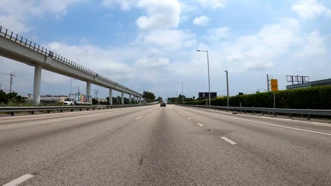 Driving highway 112 eastbound with view of Miami Metrorail on left Stock Footage