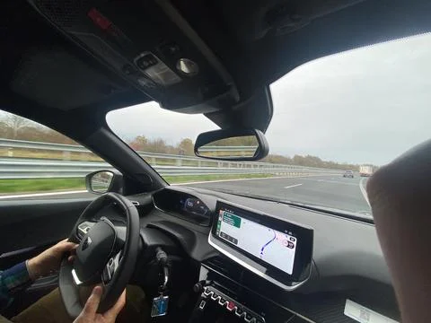 Driving on a highway with navigation system guiding the way on a cloudy day Stock Photos