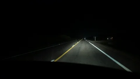 Driving on highway road at night. Driver POV in pitch dark with headlights Stock Footage