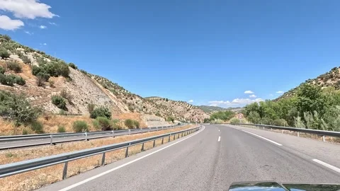Driving on a highway through a valley surrounded by hills Stock Footage 285231254