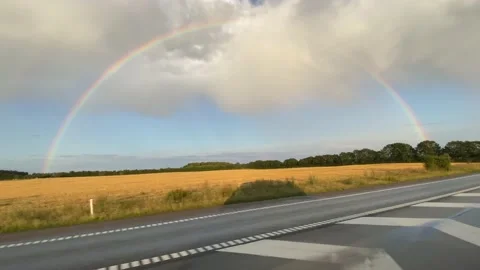 Driving on the highway while a complete rainbow shows on the side of the road Stock Footage 174858952