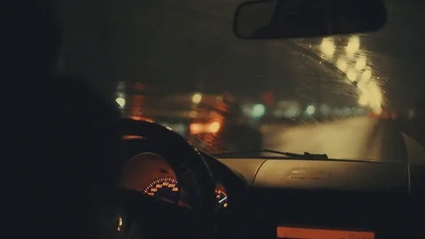 Driving on highway with working windshield wiper. Blurred city lights at night Stock Footage 80267607