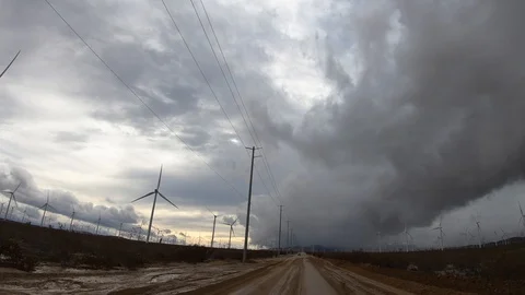 Driving Hyperlapse by windmills with storm clouds on rural road in Mojave Stock Footage