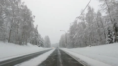Driving on icy road through winter landscape. Bad snowy and slippery weather. Stock Footage 147975256