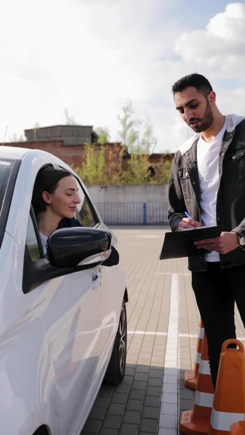 Driving instructor explaining how to drive to the female student in car Stock Footage 275011980