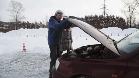Driving instructor Talks about the engine of an open car hood to pretty teenage Stock Footage 73528472