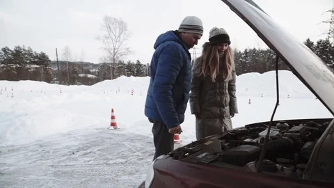 Driving instructor Talks about the engine of an open car hood to pretty teenage Stock Footage 73528579