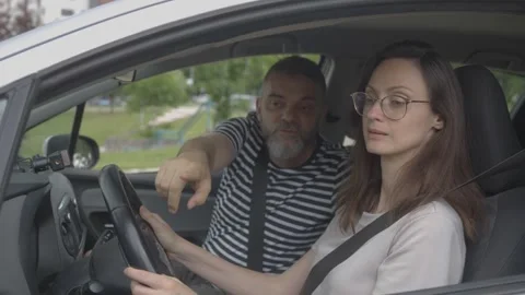 Driving instructor teaching woman to drive Stock Footage 337832948