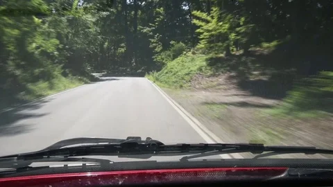 Driving on narrow road through a forest with curves, in sunlight and shade Stock Footage 79226579