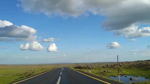 Driving on Open Highway Through Rocky Landscape Under Blue Sky 動画素材 335488444