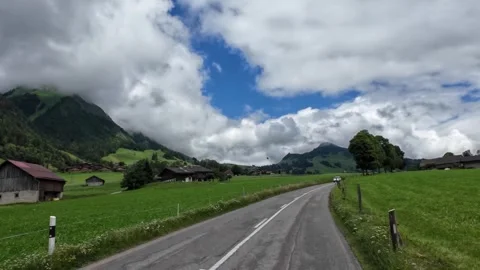 Driving Open Road with Green Meadows and Village Rooftops Stock Footage 340046160